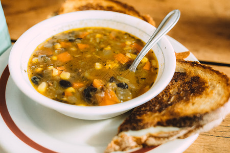 桌上烤面包的美味蔬菜汤和桌上烤面包的勺子美味蔬菜汤芹豆子西兰花图片