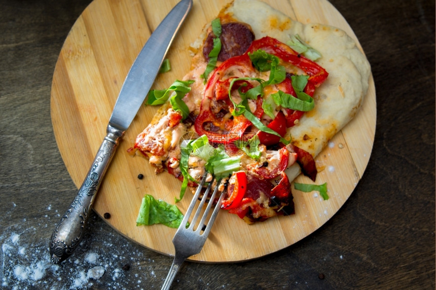 乡村刀番茄圆木板上配有胡椒培根和草药的披萨片图片