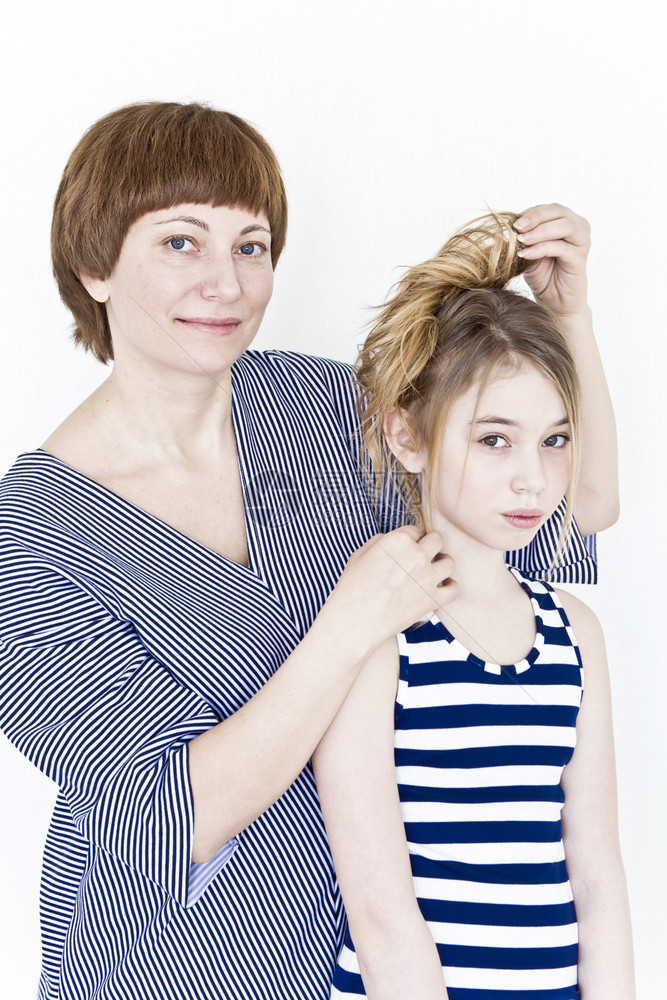 女士垂直的母亲穿着脱衣服在白墙附近给女儿做发型十二图片