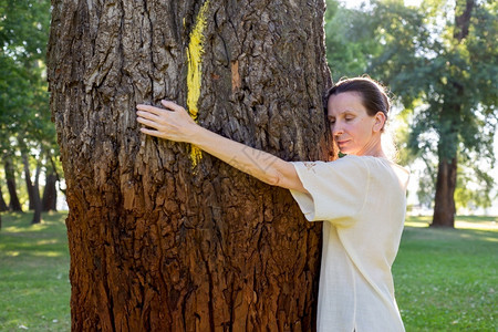 为了河一位环保主义者女正在拥抱一棵花粉树以证明爱自然和环境是的夏天图片