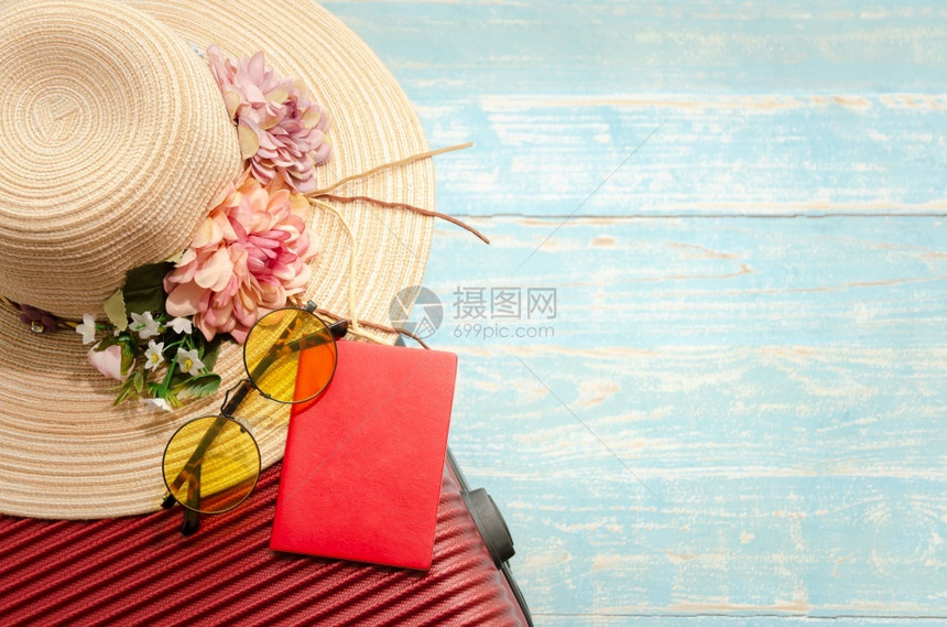 边缘眼镜蓝色的红行李护照太阳镜和花帽顶端观光旅行配件其红色李太阳镜和草花帽的蓝色浅木制背景图片