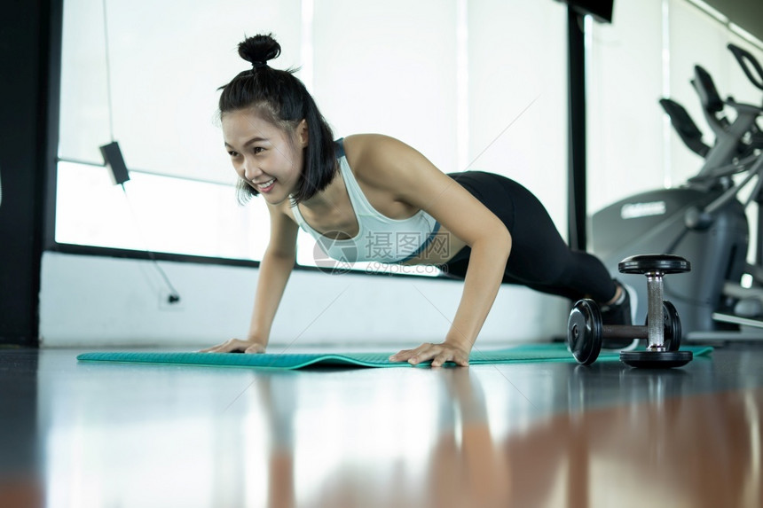 淑女参加健身培训的妇女健身穿戴高训练长子年轻女在健身时做俯卧撑在健身时做俯卧跳的肌肉女吸引人的成图片
