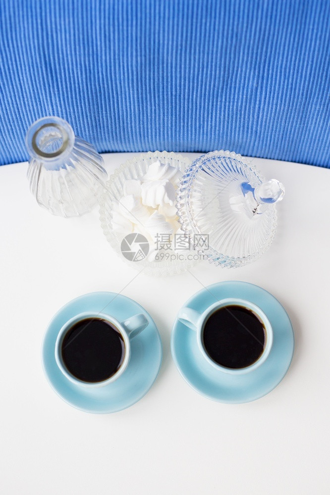 早晨食物白色的桌上有两个蓝色咖啡杯有花瓶和带棉糖的碟子桌上有两个蓝色咖啡杯有花瓶和带棉糖的碟子图片