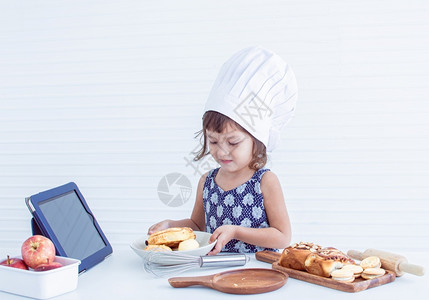 一个天主教小姑娘正在网上学习准备和做家里的面包店帽子学前班制造图片