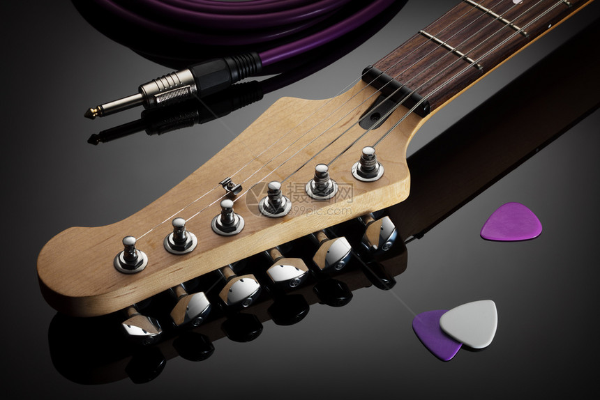电吉他的头插接电缆和听器紧贴在旁边的电吉他头接听器和插电缆旁边有反光的闪背景钉住棕色的紫图片