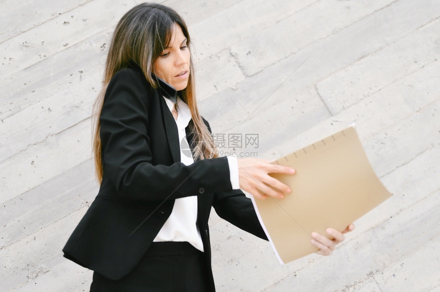 挑衅的沮丧愤怒女商人拿着手机文件高质量的照片愤怒女商人拿着手机文件劳累过度图片