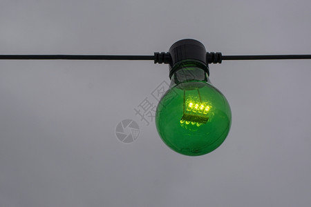 灰色天空背景的字符串上绿色颜灯泡的绿亮电技术圆形图片