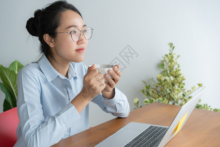 美丽思维年轻的亚洲女在家庭办公桌做笔记本电脑工作享受咖啡疲劳的图片