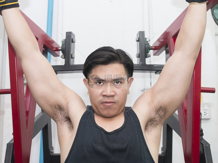 成人运动青年男子在健身机上伸胸肌肉的肖像三头锻炼图片