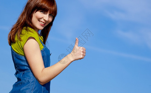 太阳夏天自由一个快乐美丽的女人肖像在蓝天上举起拇指图片