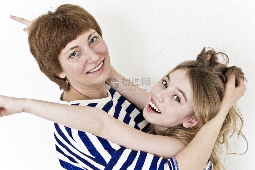 四十淑女最幸福的母亲和女儿穿着条纹衣服在白墙附近玩青少年图片