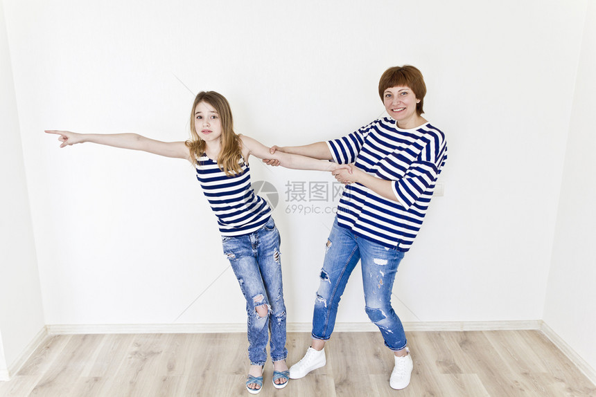 有条纹的最幸福母亲和女儿穿着条纹衣服在白墙附近玩十二垂直的图片