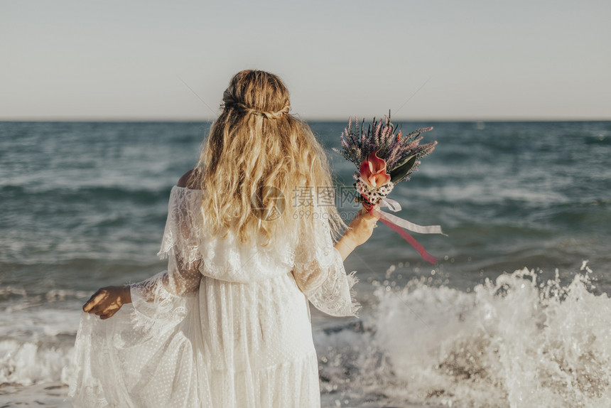新娘站在海边手拿花束图片
