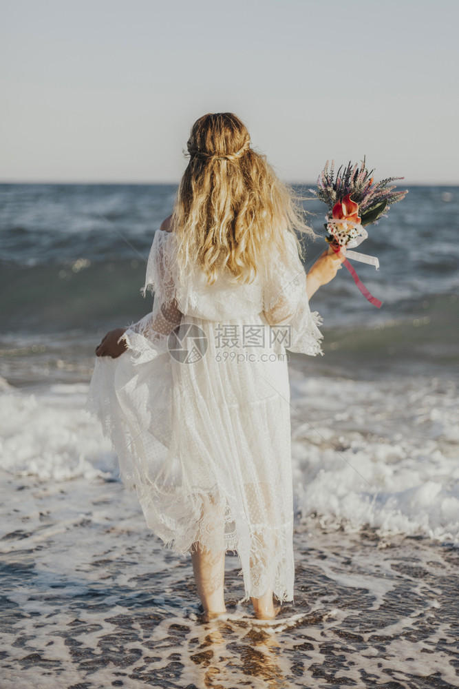 新娘站在海边手拿花束图片