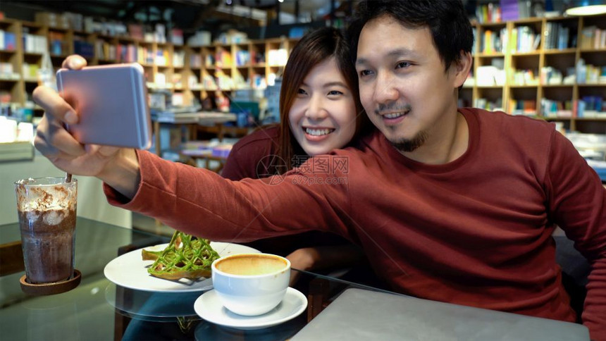 保持随意的人们亚洲夫妇在现代咖啡店或工作场所共同空间现代办公室生活方式和休闲概念中以幸福的方式自拍图片