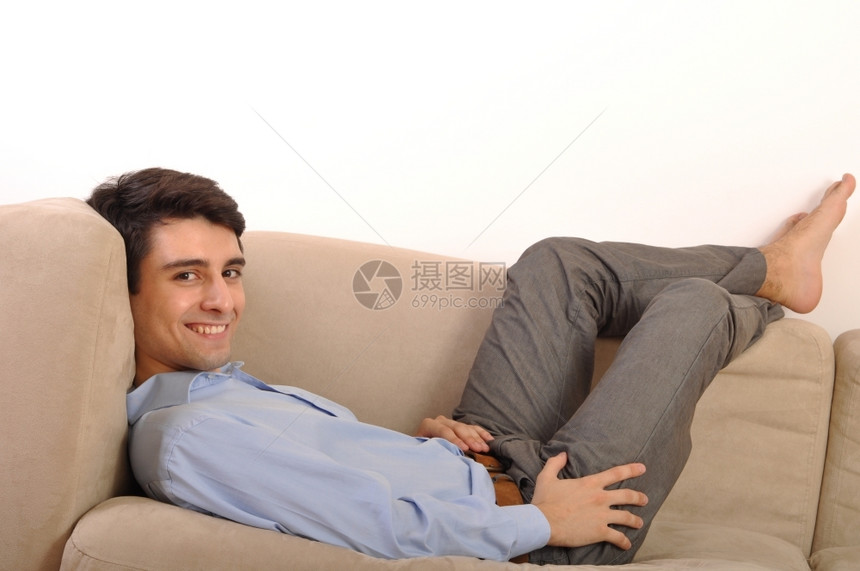 颜色迷人的年轻男子躺在沙发上着放松孤立在白色背景的沙发上男闲暇图片