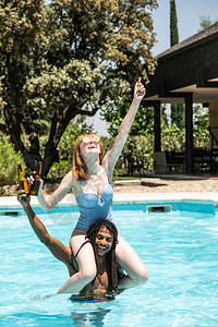 游泳的漂浮酒店非裔美国人男子和白女在游泳池里玩图片