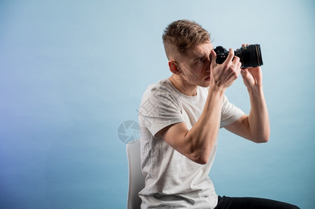 相机人像拍照影楼英俊的年轻摄影师在蓝色背景上使用相机图片