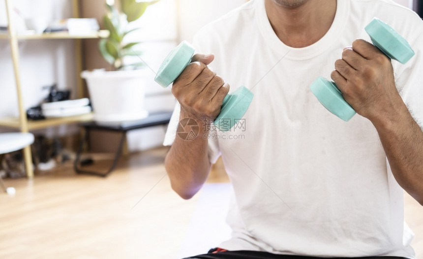 英俊的亚洲黑人男子在家庭训练习中握着哑铃体重教练室内运动锻炼健康活跃的体重健身式运动体育锻炼型重量图片