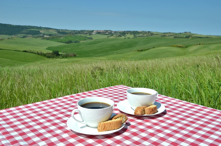 与意大利Toscan风景对抗的桌上咖啡和罐头菜锡耶纳曲奇饼烘烤的图片