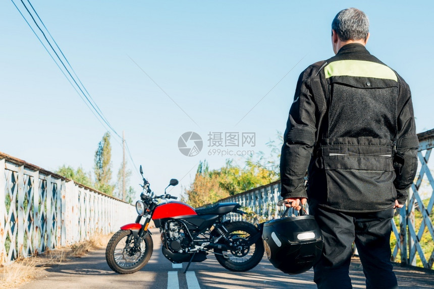 背着的男人看手里拿头盔的摩托车背着男人看手里拿头盔的摩托车自信男发动机图片