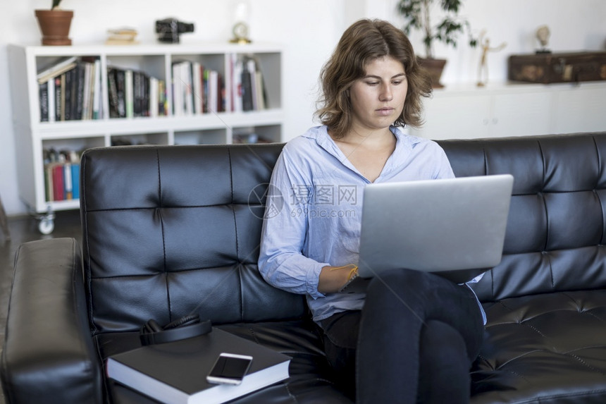 坐着技术女孩年轻妇在家里使用笔记本电脑年轻美丽的妇女在家里使用笔记本电脑图片