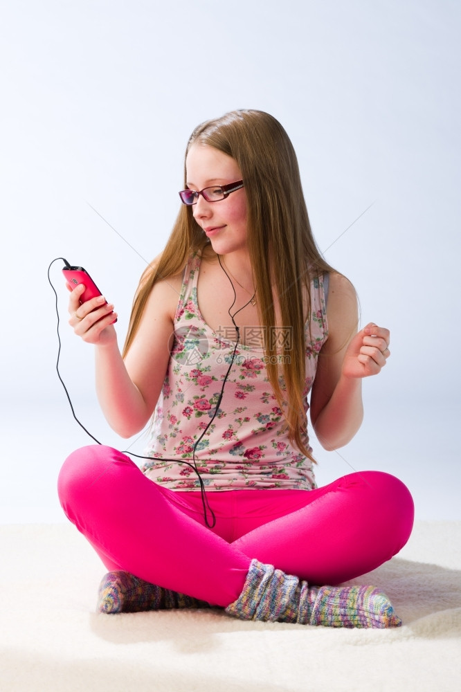 现代的一个年轻美丽女孩听着手机音乐的少女学生垂直图片