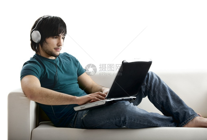 乐趣白种人年轻男坐在沙发上用笔记本电脑工作同时听音乐青少年图片