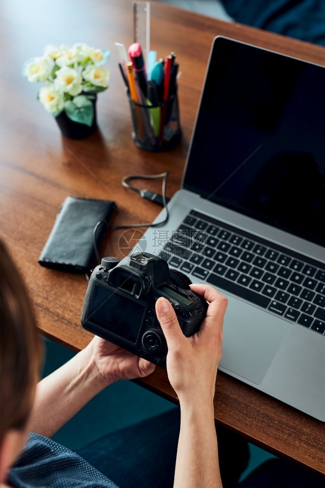 白种人拍照片在笔记本电脑和相机上拍摄照片的女影师妇编辑改用触摸浏览照片作为自由职业者坐在办公桌旁相片图片