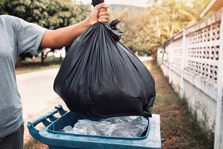 污染黑色的妇女用手把垃圾装在黑袋里清洁成垃圾环境图片