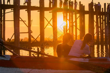 两个太阳素材喜悦游艇两个女人坐在一条船上看着河边的日落假期背景