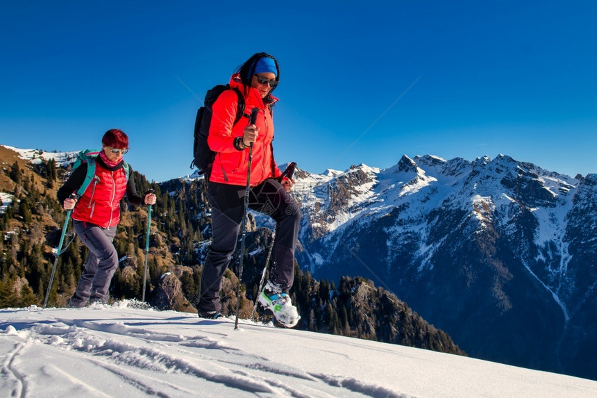 毅力冰踪迹妇女对等者在雪中从事登山活动图片