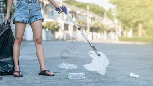 妇女使用垃圾收集器设备将塑料废物放入地面黑袋中进入关心拒绝图片