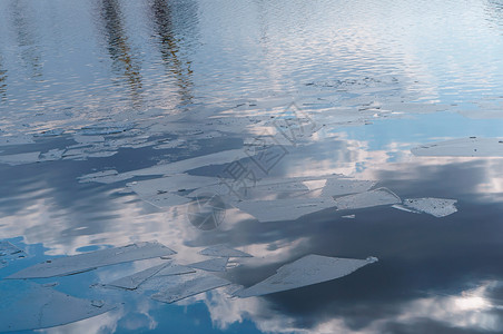 俄罗斯早春水面上的冰块中倒映的云朵在水中的云彩早春水面上冰块反射解冻图片