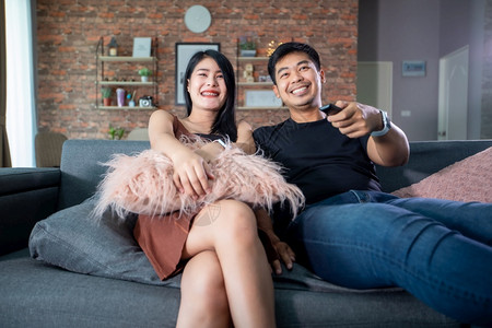 新的亚洲情侣在家沙发上看电视度假节日笑着快乐地派对观看图片