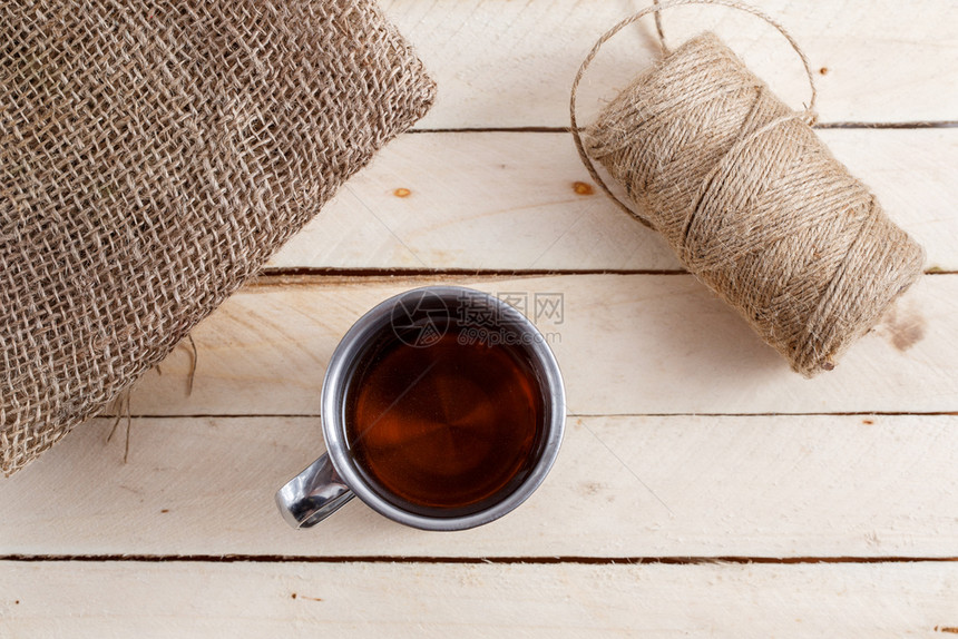 茶叶旁边的木制背景茶杯是画布和一连串的线条在茶叶旁边的木制背景上有茶的铁旧杯子下午热的线程图片