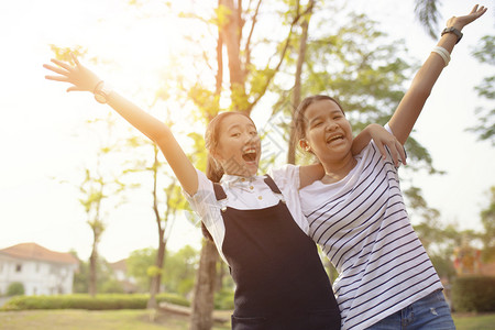 成功孩子两个亚裔青少年在绿色自然公园中带着快乐的情绪欢笑肖像图片
