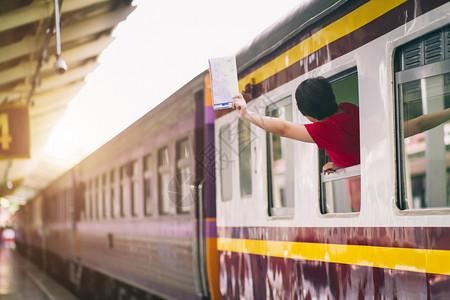 乘客女孩游身着红礼服的亚裔妇女拿着手举在火车上旅行站路打招呼图片