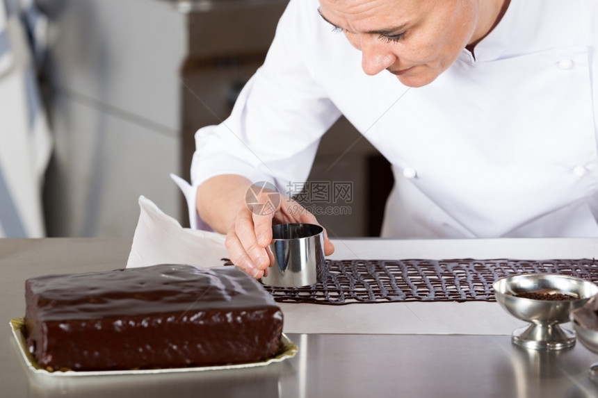 厨房的糕点师装饰巧克力蛋糕钢包面师甜的图片