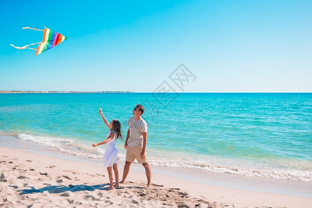 父亲和女儿在夏天沙滩上玩风筝图片