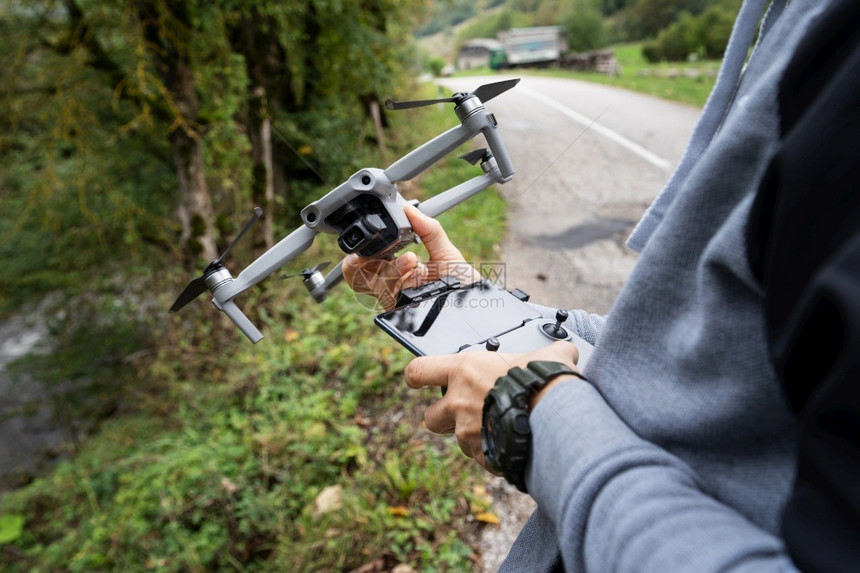 控制器小工具近距离接无人机和遥控器掌握在秋天站路边的不明人物手中图片