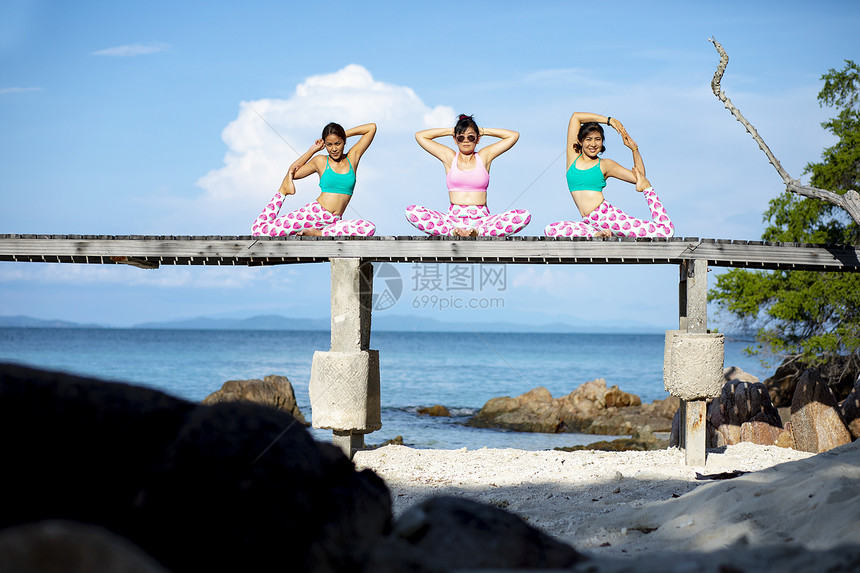三个亚洲女人在海滩码头做瑜伽姿势天空玩假期图片