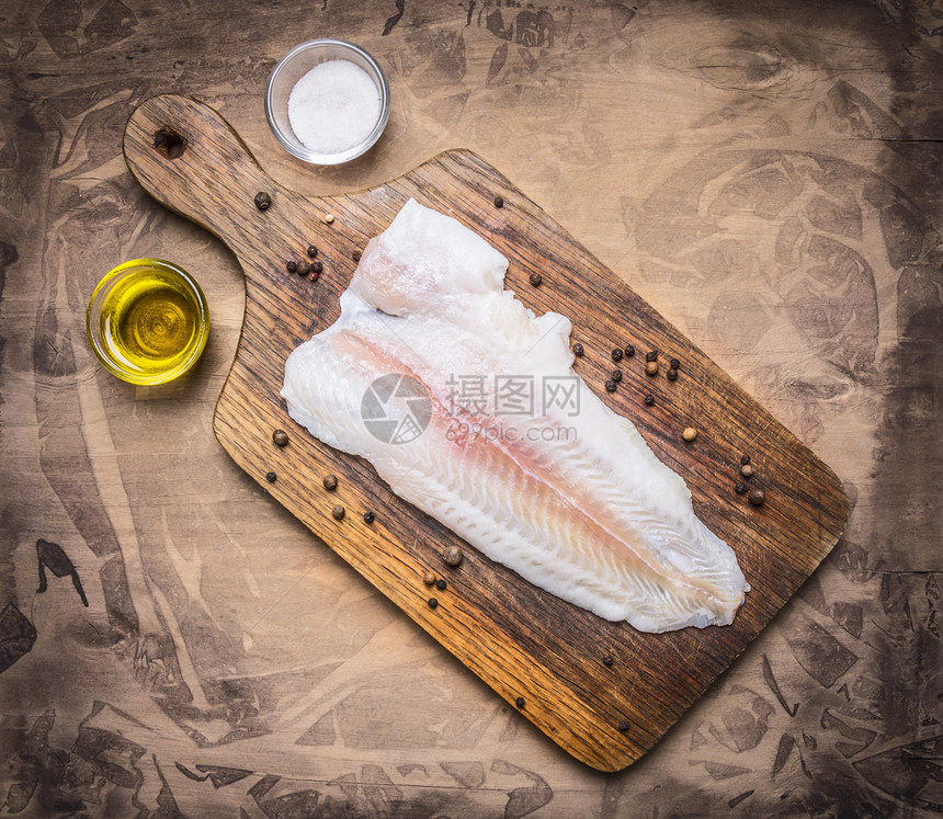 饮食鱼树叶木制生锈背景的顶端视图接近处上面有黄油和盐的剪切板上原油Pangasius图片