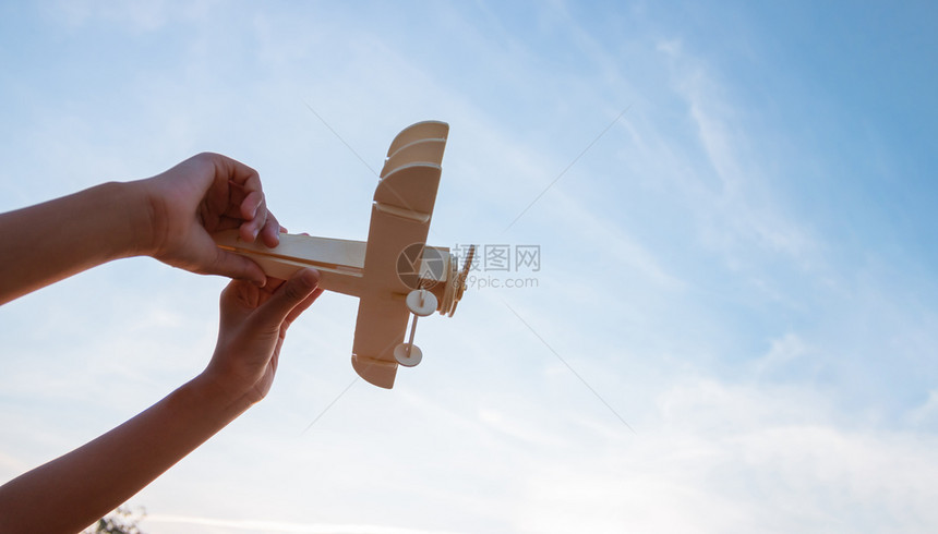 自由快乐的孩子玩木具飞机在日落的天空背景上男生航班图片