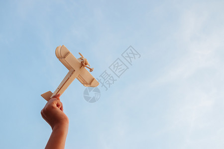 航班笑快乐的孩子玩木具飞机在日落的天空背景上灵感图片