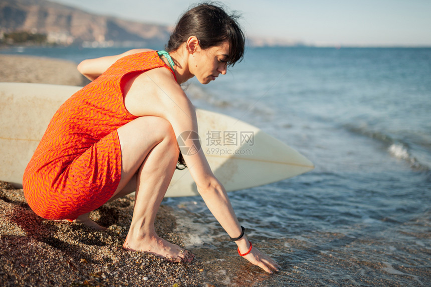 沙滩上年轻女孩带着冲浪板等着海浪图片
