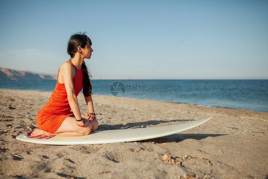 沙滩上年轻女孩带着冲浪板等着海浪图片