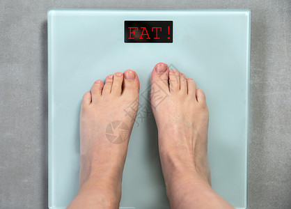 吃脚信息常设脚丫子数字体重秤上的脚带有单词FAT顶视图消息不健康的生活方式减肥消息帮助概念关闭数字体重秤上的脚帮助概念背景