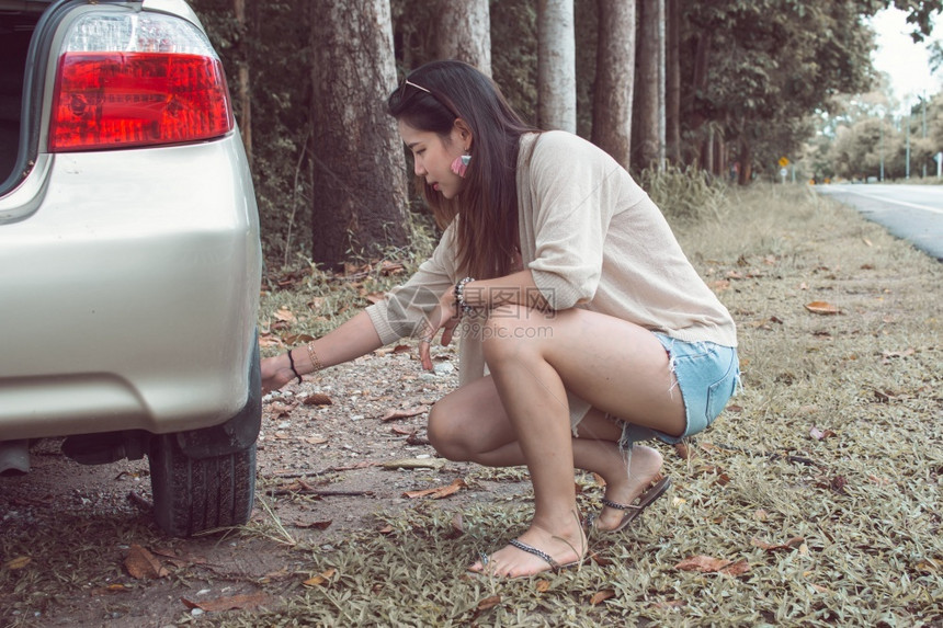 一名亚洲妇女试图修补在街头旁边的破碎汽车同时乘坐节假日汽车保险和暑假的概念一名亚洲妇女夏天旅游户外图片