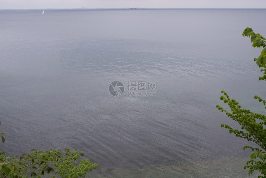 自然向欧洲从哥本哈根以北丹麦海岸到瑞典有树木和叶波罗的海景灰色云雾波罗的海景与船只相隔很远的波罗海景与灰云图片